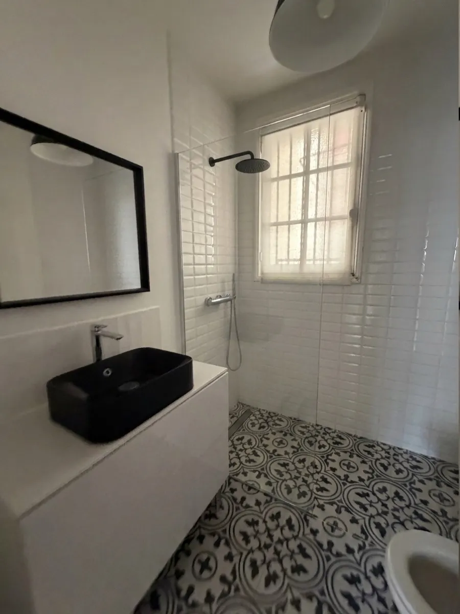 La même salle de bain après travaux : la baignoire est remplacée par une douche à l'italienne avec paroi vitrée