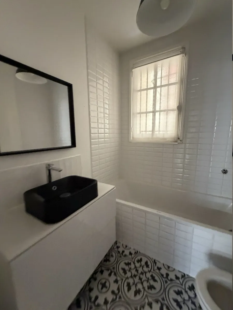 Salle de bain avant travaux : baignoire encastrée, carrelage métro blanc et sol en carreaux de ciment