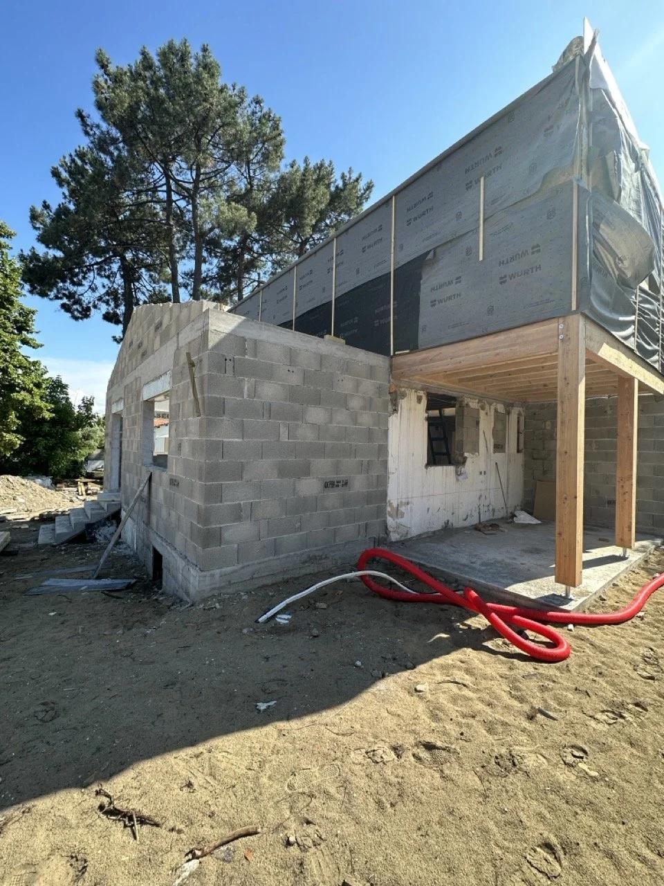Chantier de surélévation d'une maison : murs en parpaings, ossature bois et pare-pluie sur l'étage créé